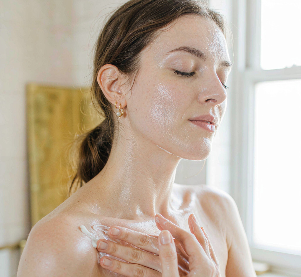 Woman gently massaging firming cream onto her decollete in soft daylight